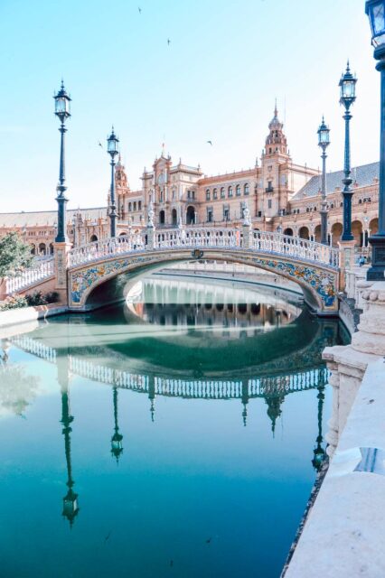 bridge lampposts body of water and buildings during day